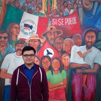 alum Eddie Garcia in front of 'si se puede' mural