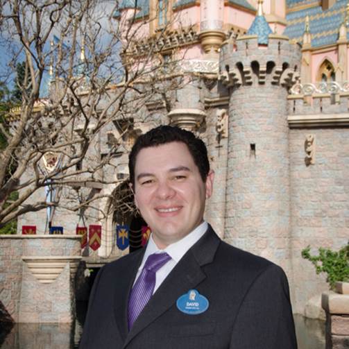 alum David Hernandez in front of castle at Disneyland
